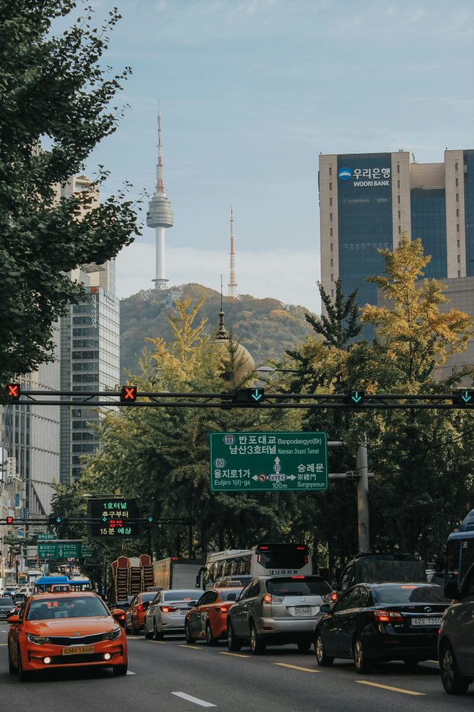 Seoul street view with N Seoul Tower rising behind office buildings and traffic on a downtown road