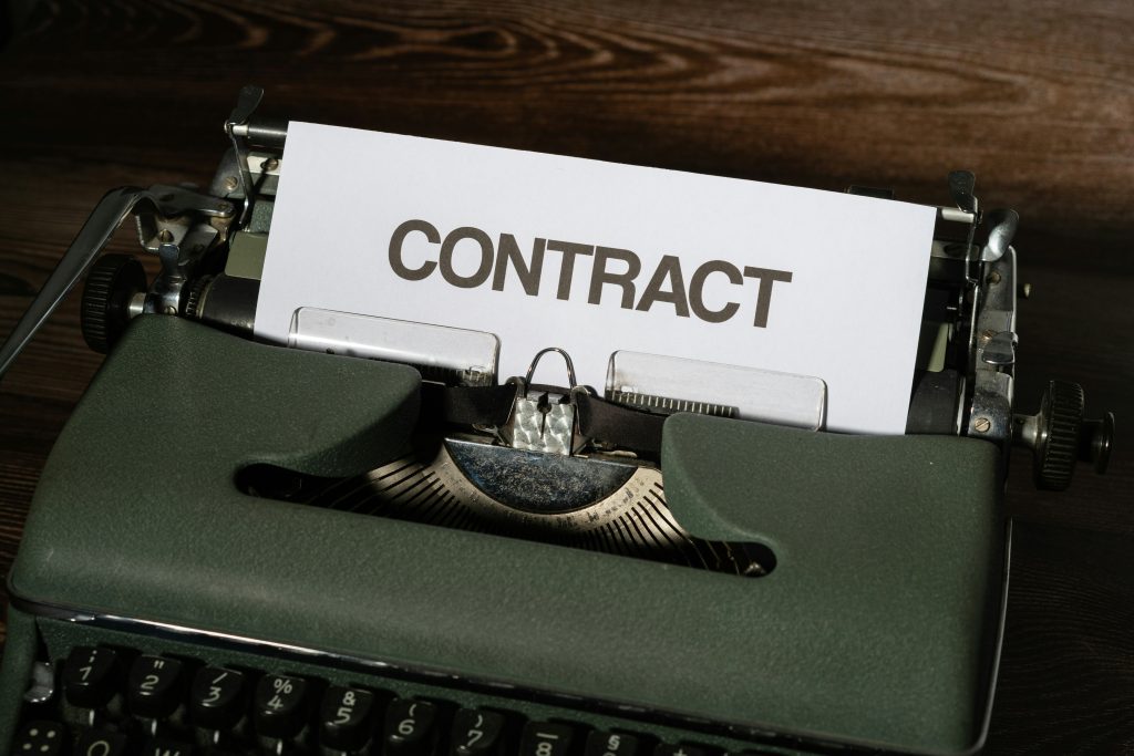 A sheet of paper reading CONTRACT rolled into a vintage green typewriter